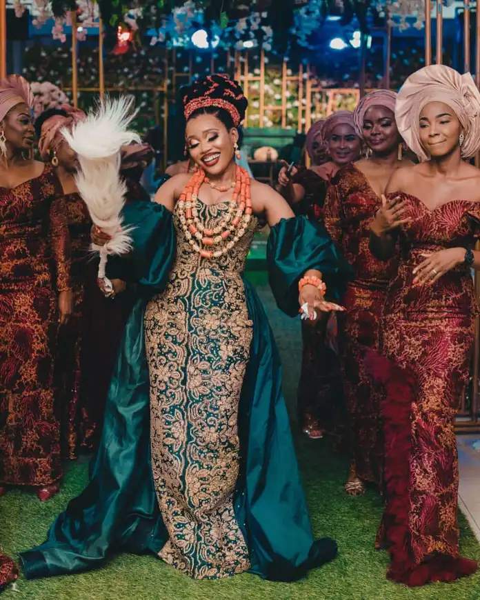 A radiant Igbo bride dressed in traditional bridal attire, adorned with vibrant green and gold fabrics, showcasing intricate embroidery and patterns that symbolize the rich cultural heritage of the Igbo people,