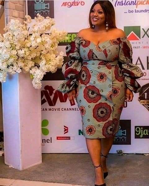 Ankara Gown Styles for Plus-Size Ladies in 2023: A fashionable model wears an Off-Shoulder Peplum Sleeve Ankara Gown with stunning African prints, epitomizing the elegance of African fashion.